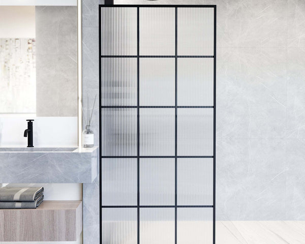 Matte black framed shower screen with a mosaic-textured glass panel in a warm, minimal bathroom