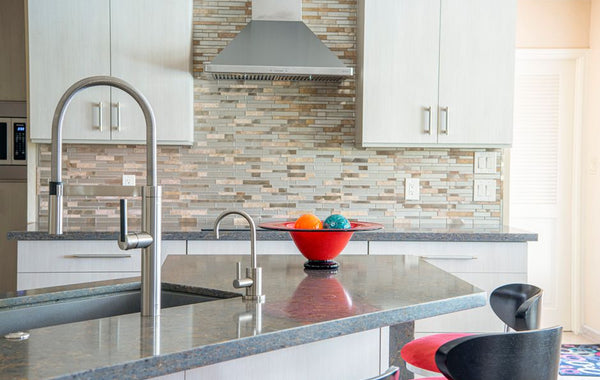 Contemporary kitchen interior with a sleek faucet and colorful fruit bowl on granite countertop.