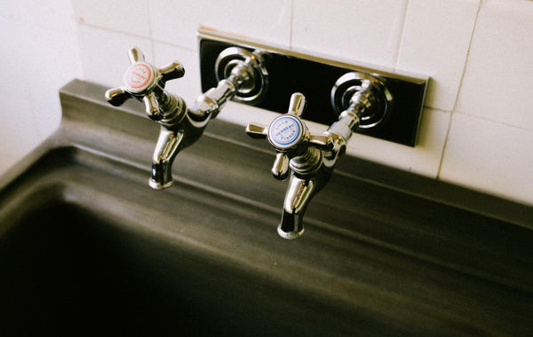 Detailed view of chrome sink faucets with classic hot and cold labels in a kitchen setting.