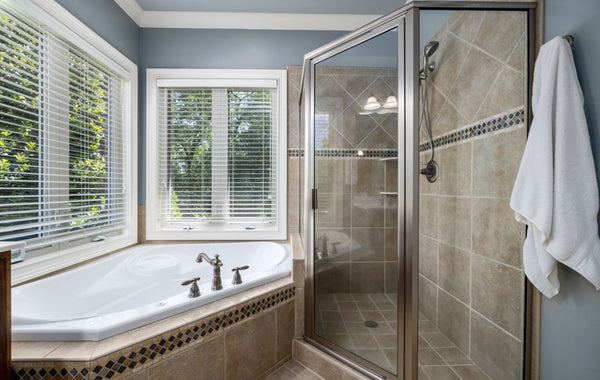 Elegant bathroom with glass shower, soaking tub, and large windows offering natural light.