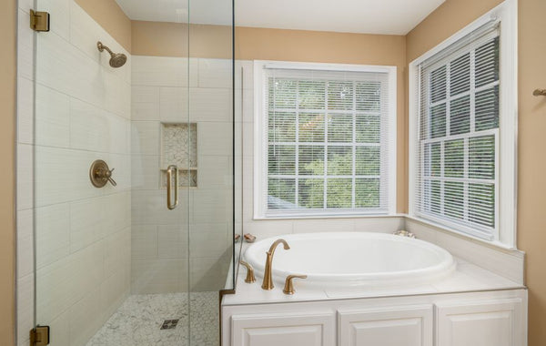 Elegant modern bathroom featuring a bathtub with gold fixtures and a glass-enclosed shower with tiles.