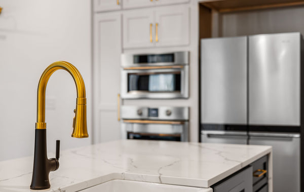 Elegant kitchen interior with a modern gold faucet and sleek stainless steel appliances.