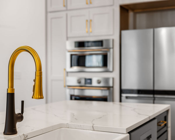 Elegant kitchen interior with a modern gold faucet and sleek stainless steel appliances.