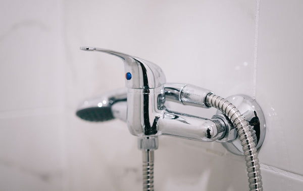 A detailed view of a sleek chrome shower faucet in a clean bathroom setting.