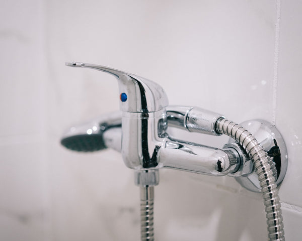 A detailed view of a sleek chrome shower faucet in a clean bathroom setting.
