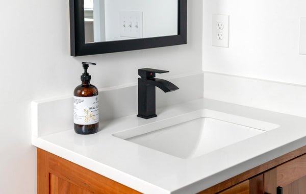 Stylish bathroom setup featuring a sleek black faucet, wall mirror, and elegant countertop.