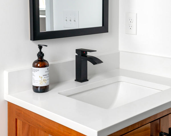 Stylish bathroom setup featuring a sleek black faucet, wall mirror, and elegant countertop.
