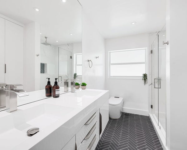 Modern white bathroom featuring sleek fixtures and herringbone flooring design.