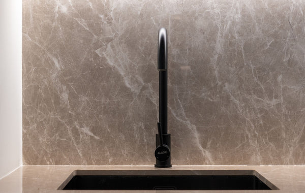 A stylish kitchen sink with a marble backsplash and black faucet. Ideal for modern home designs.