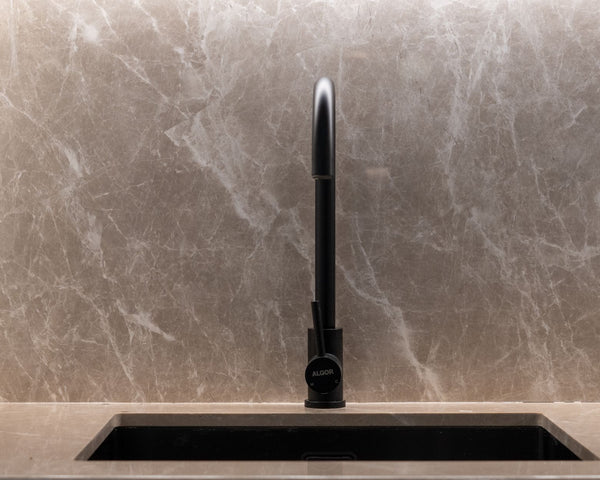 A stylish kitchen sink with a marble backsplash and black faucet. Ideal for modern home designs.