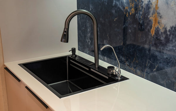 Sleek kitchen faucet with a black sink against a marble backsplash, highlighting modern interior design.