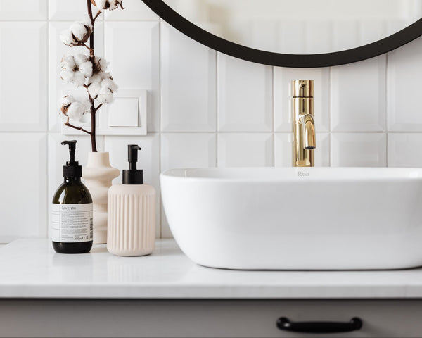 Stylish minimalist bathroom with a ceramic basin and modern gold faucet.