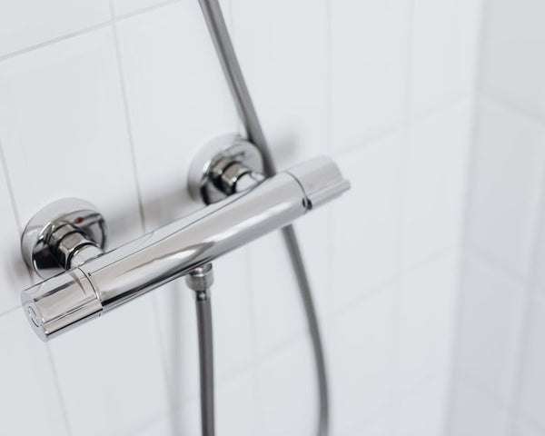 Modern chrome shower faucet on white tiled wall, elegant and clean design.