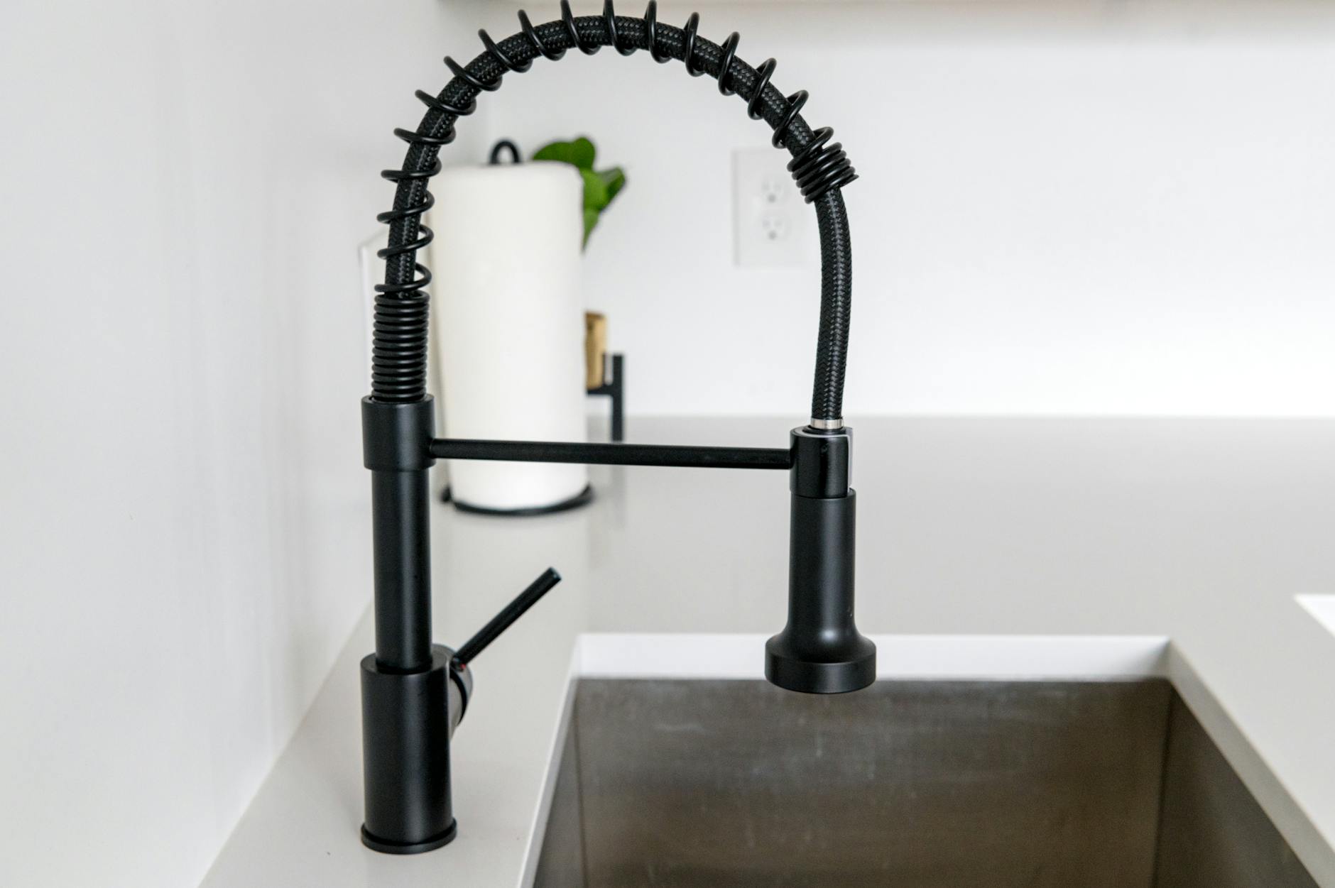 Sleek black faucet on white countertop in modern kitchen. Ideal for minimalist and contemporary designs.