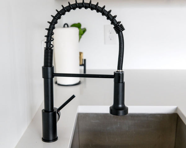 Sleek black faucet on white countertop in modern kitchen. Ideal for minimalist and contemporary designs.