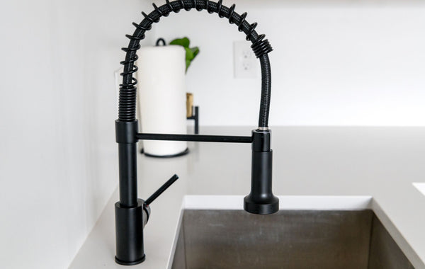 Sleek black faucet on white countertop in modern kitchen. Ideal for minimalist and contemporary designs.