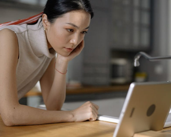 An engaged woman using a tablet device while leaning on a kitchen counter indoors.