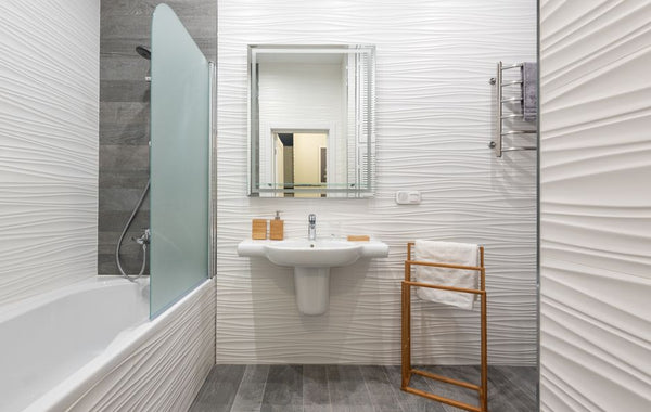 Contemporary bathroom interior with bathtub and washstand with toiletry products under mirror in light house