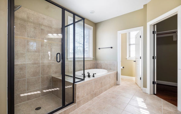 Spacious and bright bathroom featuring glass shower and built-in bathtub with natural light.