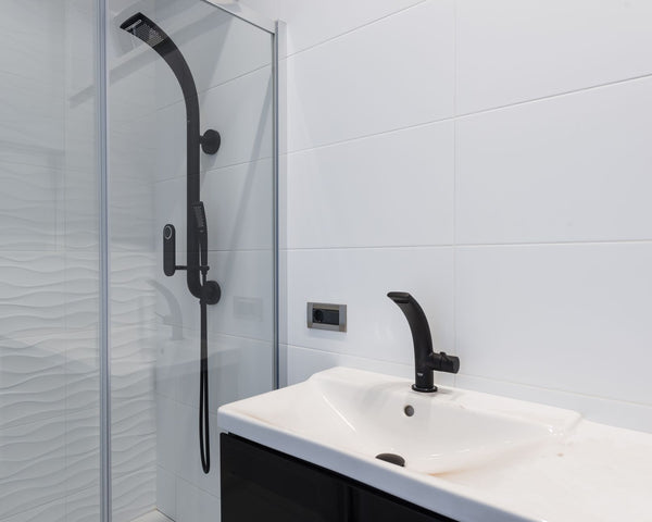 Modern minimalist style interior design of bathroom with white tiled walls and washbasin and black faucet and shower unit with glass partition