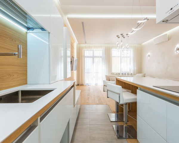 Interior of spacious kitchen with new white furniture with wooden details in luxury apartment in daylight