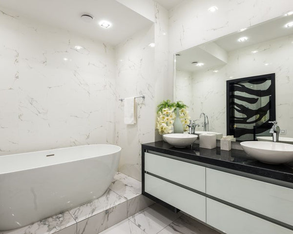 Interior of contemporary bathroom with white marble bathtub tiled walls and floor and cabinet under sink with chrome faucet