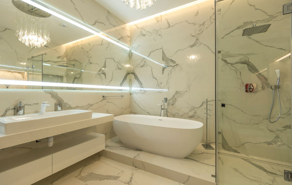 Elegant marble bathroom with bathtub, sink, and glass shower enclosure.