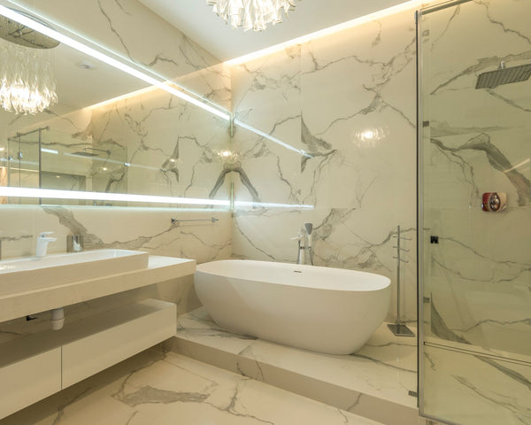 Elegant marble bathroom with bathtub, sink, and glass shower enclosure.