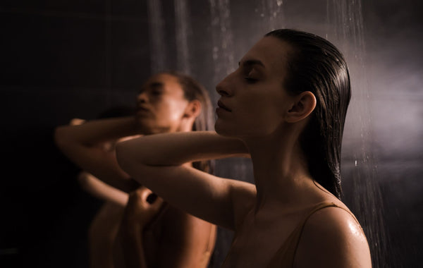 Two women enjoying a calming shower experience in a serene spa environment.