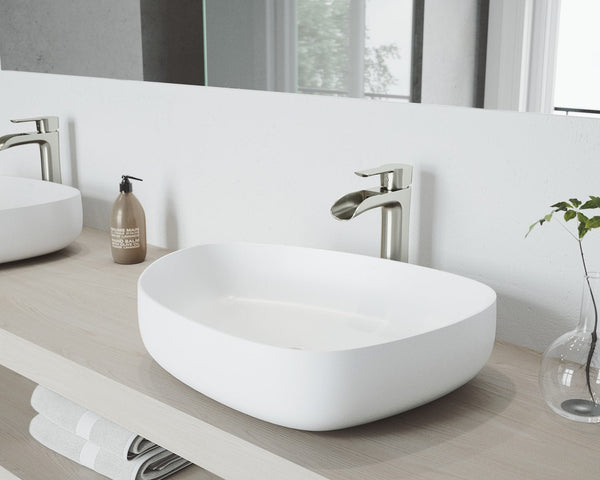 White VIGO Apollo Peony matte stone vessel sink with a tall brushed nickel vessel faucet on a light wood vanity top