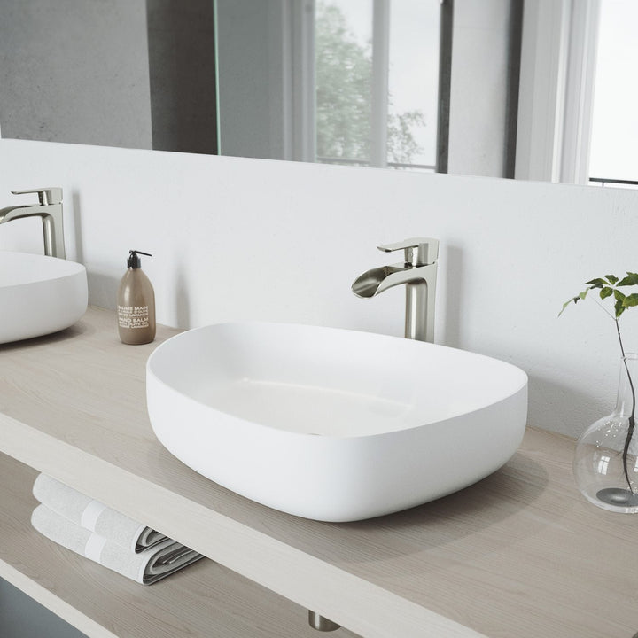 White VIGO Apollo Peony matte stone vessel sink with a tall brushed nickel vessel faucet on a light wood vanity top